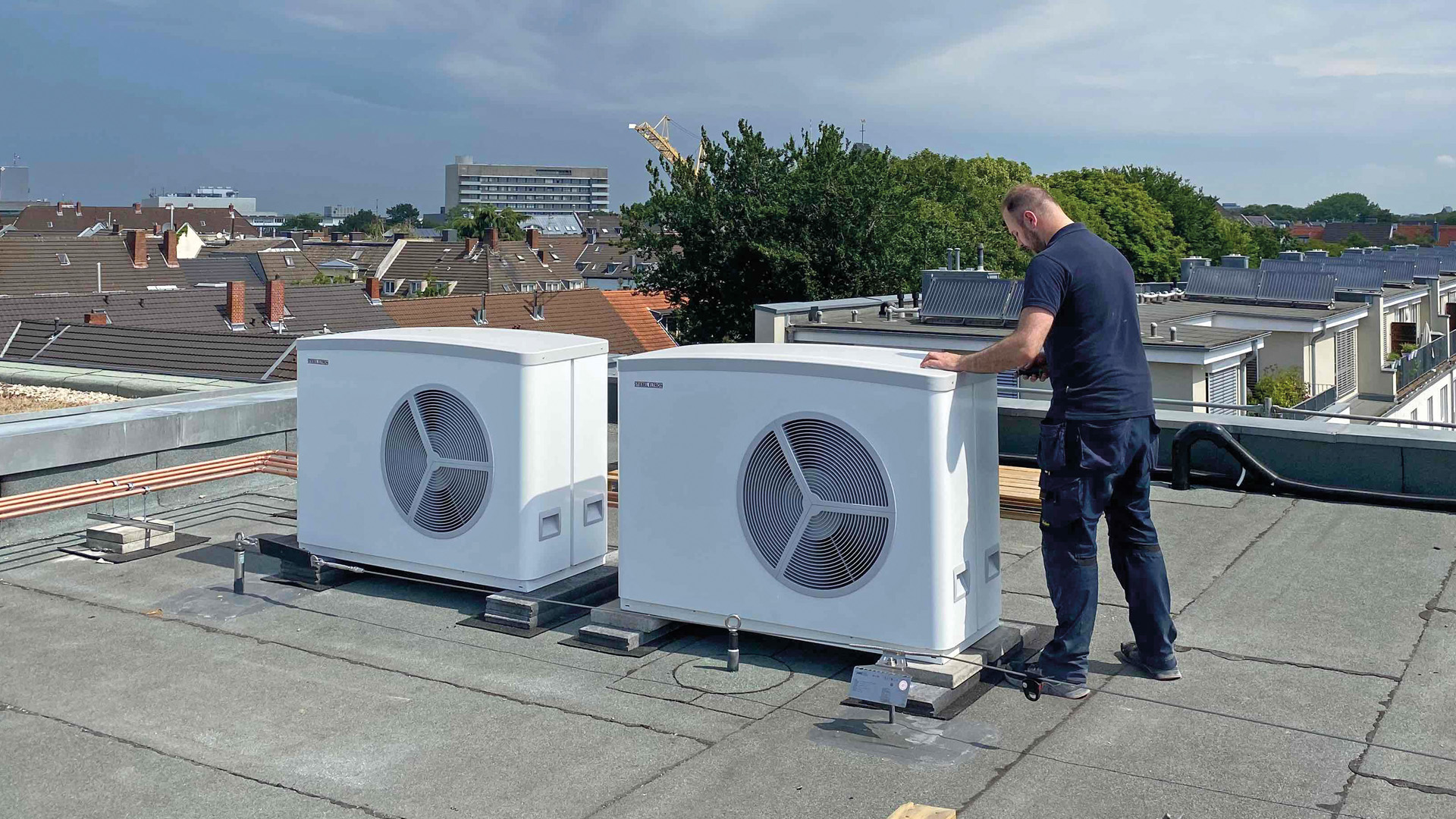 Ein Techniker installiert eine Wärmepumpe auf dem Dach eines Sülzer Wohnhauses